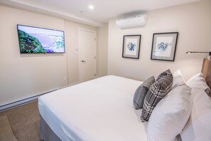 A bedroom with a bed, a TV mounted on the wall, and two framed pictures. - Pinnacle Ridge 23 - Ski in Ski out, Private Hot Tub, Gas Fireplace (Whistler)