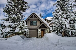 A two-story log cabin with a stone foundation, surrounded by snow-covered trees. - Pinnacle Ridge 23 - Ski in Ski out, Private Hot Tub, Gas Fireplace (Whistler)