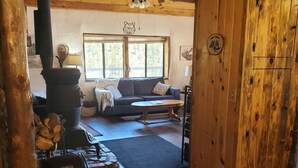 Un interior rústico de madera con chimenea de piedra, un sofá y una puerta de madera grande.