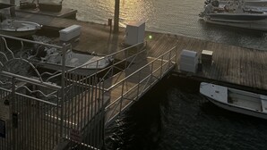 A marina with boats docked, a wooden pier, and a clear sky with the sun setting. - Large Beach House for Bigger, Better Gatherings! (Folly Beach)