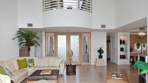 A spacious living area with a high ceiling, a sofa set, a coffee table, and a dining area with a lamp. -  Access to Mauna Lani Spa/Tennis/Pickleball/Gym/Lap Pool included with booking (Waimea)