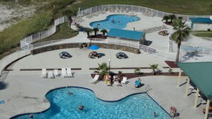 A large outdoor swimming pool area with multiple pools, lounge chairs, and a covered seating area.