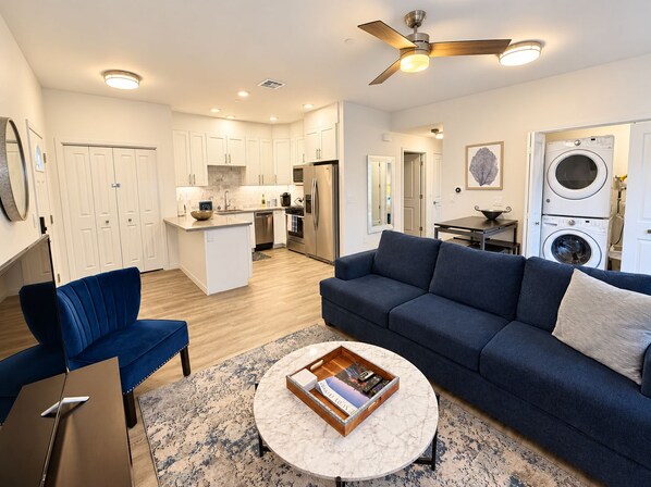 A modern apartment with a living room, kitchen, and laundry area.