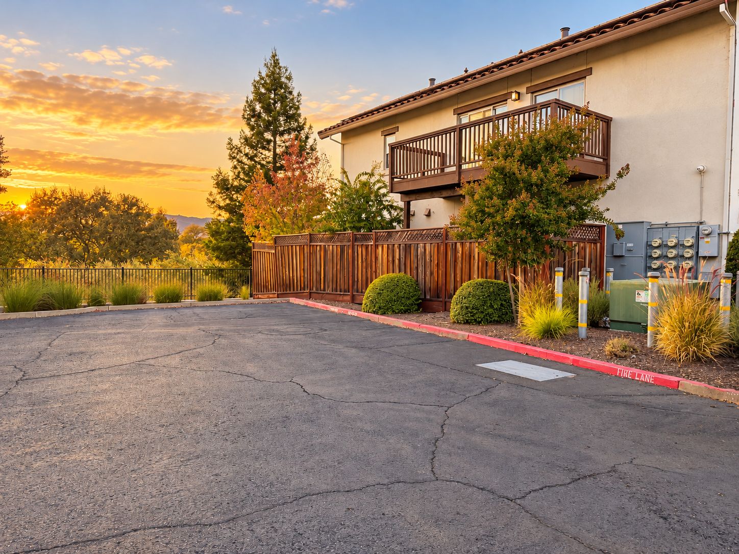 A residential building with a balcony, a fenced driveway, and a fire lane.