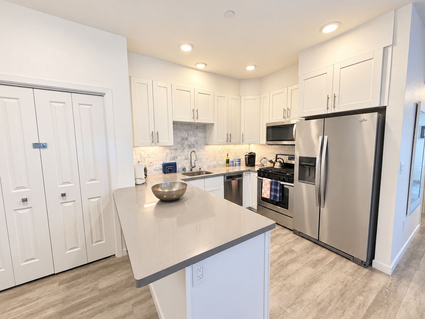 A modern kitchen with white cabinets, a stainless steel refrigerator, and a central island.