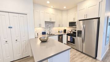 A modern kitchen with white cabinets, a stainless steel refrigerator, and a central island.