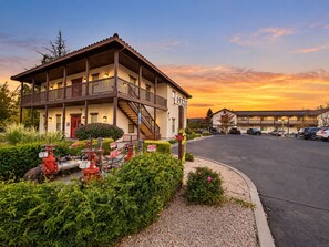 A two-story building with a balcony, a parking lot, and a sunset sky. - Sonoma 2BR Condo | 2 Private Patios, Kitchen & A/C (Sonoma)