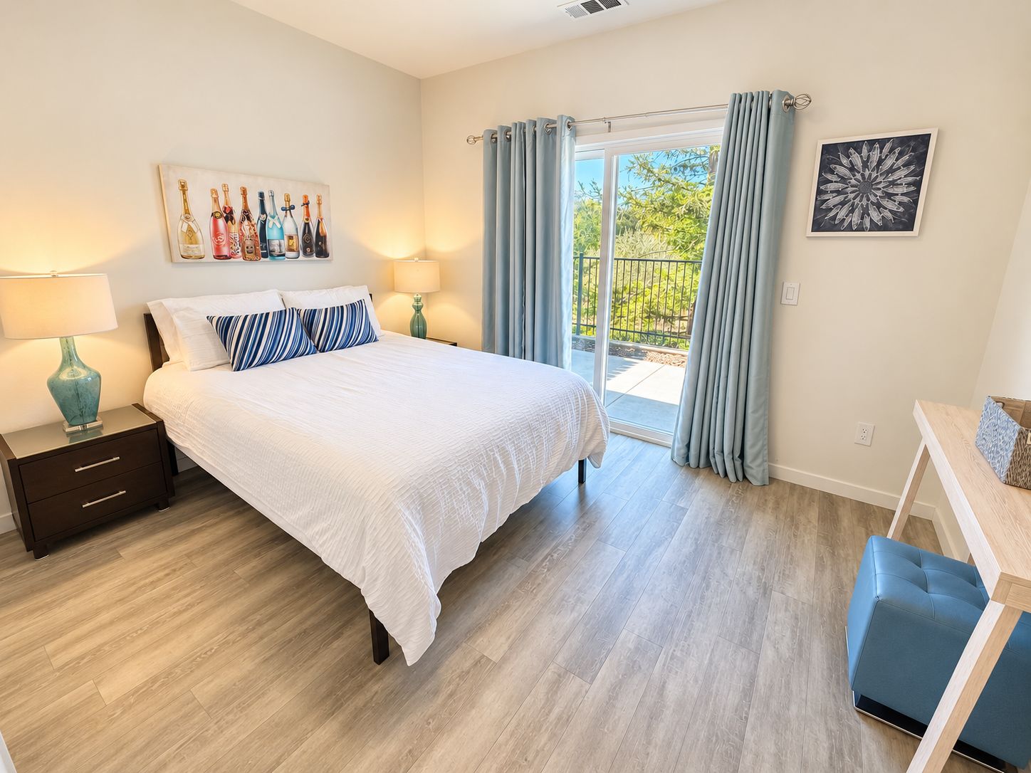 Un dormitorio con cama, mesitas de noche, una ventana con cortinas y vistas al exterior con vegetación, además de un cuadro en la pared.