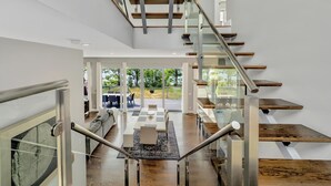 A modern staircase with glass railings and wooden steps leading to an upper level.