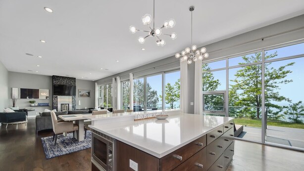 A modern kitchen with a large island, large windows, and a view of the outdoors.