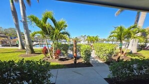 A paved pathway leading to a marina with palm trees and a grassy area. - Right on the Waterfront Marina - Suite 117 - 7150 N Tamiami Tail, Sarasota FL (Sarasota)