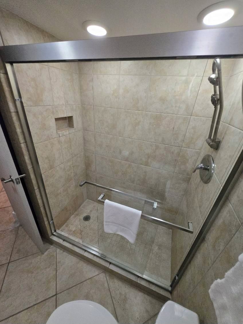 Box de vidro com porta, porta-toalhas e um pequeno nicho.