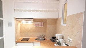 Cocina compacta con encimera de madera, un lavamanos, horno integrado y salpicadero azulejado.