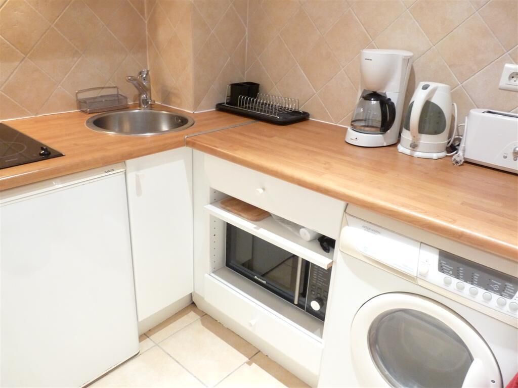 A compact kitchen with a sink, microwave, oven, and built-in washing machine.