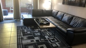 A living room with a black leather sofa, a wooden coffee table, and a patterned rug. - Old Town Scottsdale  (Scottsdale)