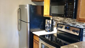 A kitchen with wooden cabinets, stainless steel appliances, a microwave, a coffee maker, and a stove. - Old Town Scottsdale  (Scottsdale)