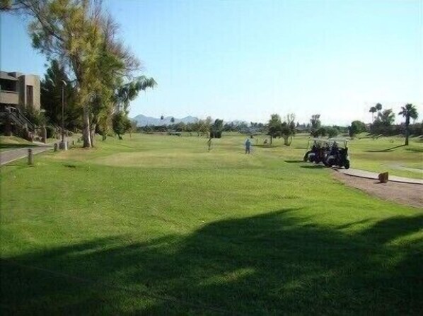 A golf course with a clear path, trees, and a distant mountain range.