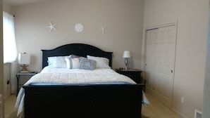 A neatly made bed with a dark headboard, two bedside tables with lamps, and starfish wall decor. - Condo conveniently located in the Heart of Old Town Florence (Florence)