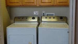 A laundry room with two front-loading washers and dryers, wooden cabinets above, and a 'CLEAN' sign on the wall. - Condo conveniently located in the Heart of Old Town Florence (Florence)
