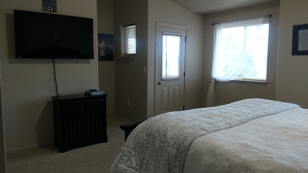 A bedroom with a bed, a TV mounted on the wall, a door, and a window with blinds. - Condo conveniently located in the Heart of Old Town Florence (Florence)