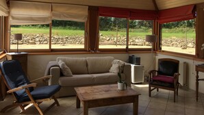 A cozy room with a sloped ceiling, a sofa, a rocking chair, a table, and a potted plant. - Breton farmhouse quiet, between sea and river (Lannion)