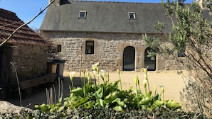 A stone building with a sloped roof, arched windows, and a chimney. - Breton farmhouse quiet, between sea and river (Lannion)