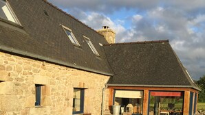 A stone building with a wooden deck, outdoor seating, and a covered area with a view of the landscape. - Breton farmhouse quiet, between sea and river (Lannion)