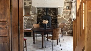 A stone-walled room with a fireplace, wooden furniture, and a tiled floor. - Breton farmhouse quiet, between sea and river (Lannion)