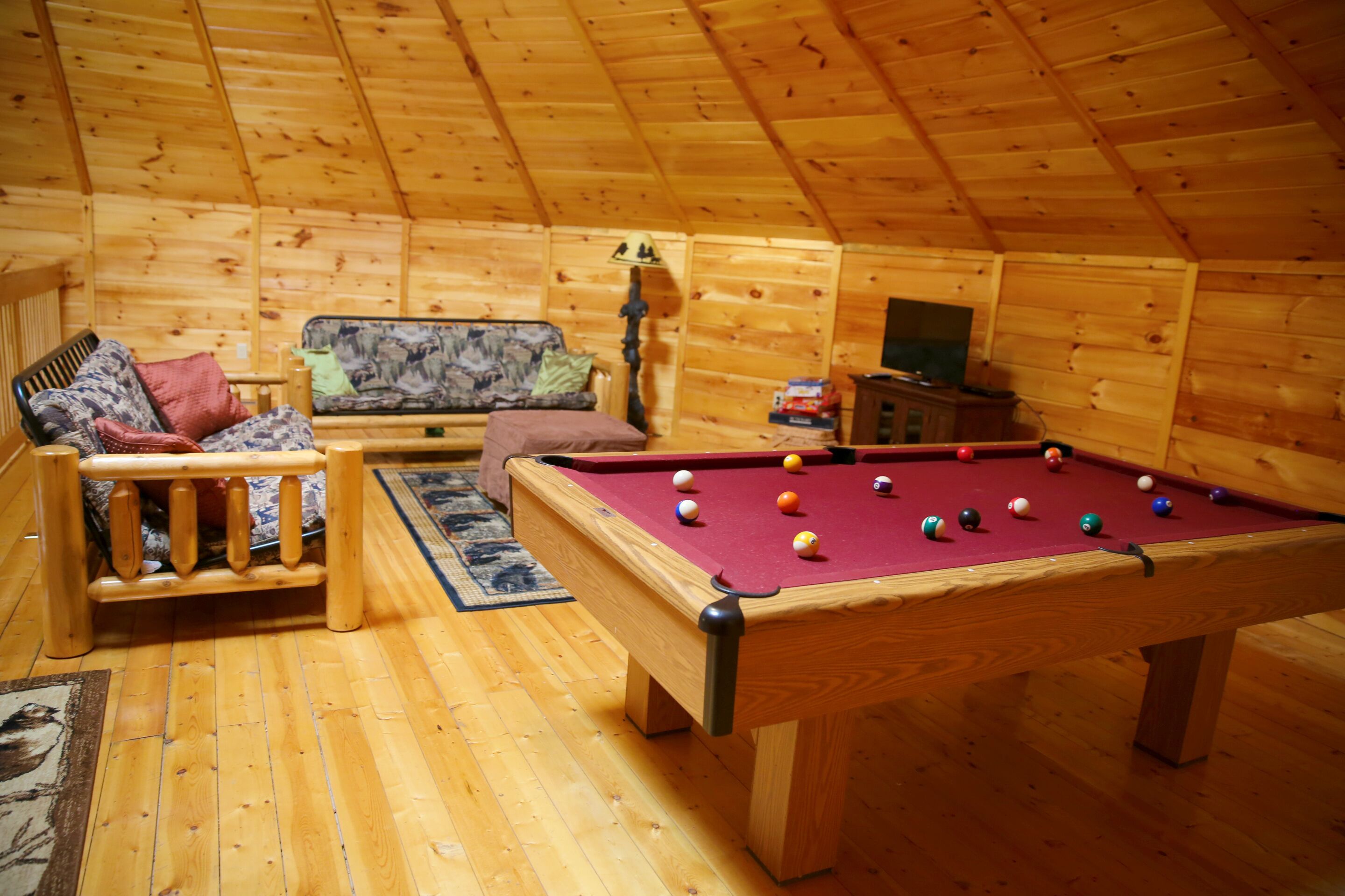 Una stanza accogliente con tavolo da biliardo, divano e soffitto in legno.