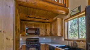 Una cocina con armarios de madera, una estufa y un ventanal.