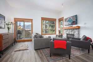Una sala de estar con chimenea, televisor y vistas a las montañas.