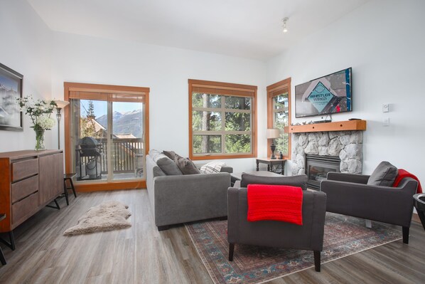 A living room with a fireplace, a television, and a view of the mountains.