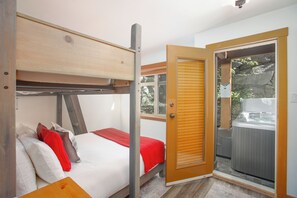 A bedroom with a bunk bed, a wooden door, and a hot tub visible through the door. - Mountain Star 16 - Ski in Walk out, Private Hot Tub, Fireplace (Whistler)