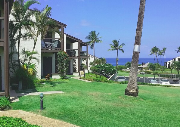 A modern hotel with a two-story structure, a covered outdoor seating area, and a view of the ocean.