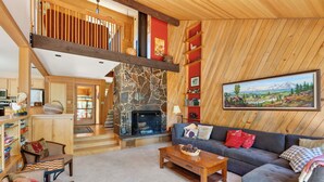 Un salón espacioso con chimenea, estantes de madera y un cuadro grande.