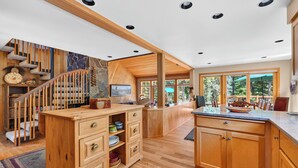 Una cocina moderna con armarios de madera, estufa integrada y un amplio ventanal con vistas a un jardín.