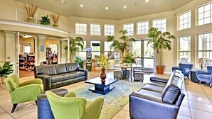 A spacious lobby with a curved seating area, a coffee table, and several potted plants. - R-disney Palms Retreat -  3 Miles To Walt Disney World (Kissimmee)