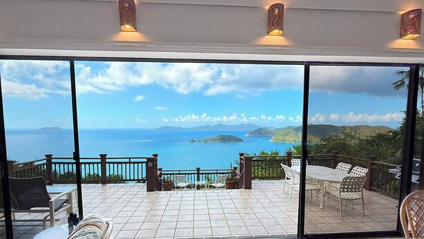 A terrace with a view of the sea, furnished with chairs and tables, and a railing. - Bask in Beauty: Anole Offers Unmatched North Shore Views and a Pool Perfect for Relaxation (Cinnamon Bay)