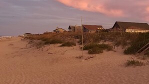 A beach with sand dunes and buildings in the background. - Cozy Cottage in Kitty Hawk with Gorgeous Ocean Views! (Kitty Hawk)