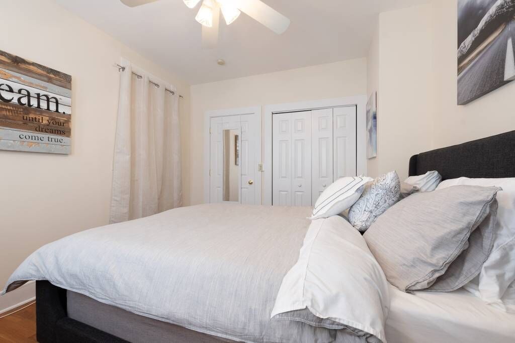 Un dormitorio con cama, cortinas, ventilador de techo y una puerta.