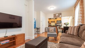 Ein modernes Wohnzimmer mit Flachbildfernseher, braunem Sofa, grauem Sessel und einer Holz-Unterhaltungsecke.