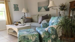 A living room with a sofa, a coffee table, and a lamp. - High Hedges Cottage  - Close to downtown Mt Dora in quiet neighborhood (Mt Dora)