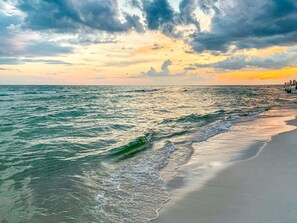 A beach with waves and a sunset.