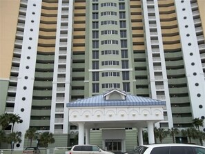 Un hotel de varios pisos con una entrada central y balcones en cada planta.