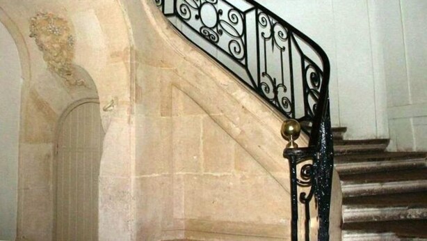 A staircase with ornate black metal railings and a brass door knocker.