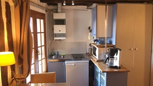 A compact kitchen with a sink, stove, microwave, and a coffee maker.