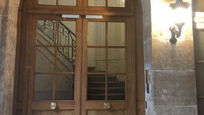 A wooden double door with glass panels and a metal staircase leading to an upper level.