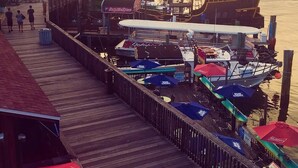 A pier with boats docked, a wooden walkway, and a view of the water.