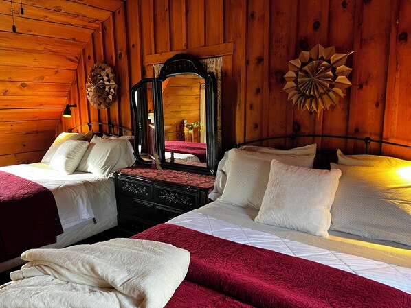 A wooden cabin room with two beds, a mirror, and a decorative wall piece.