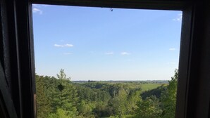 A view from a window with a wooden frame, overlooking a green landscape with trees and a clear sky. - Heritage hideaway-Secluded Log Cabin (Chatfield)